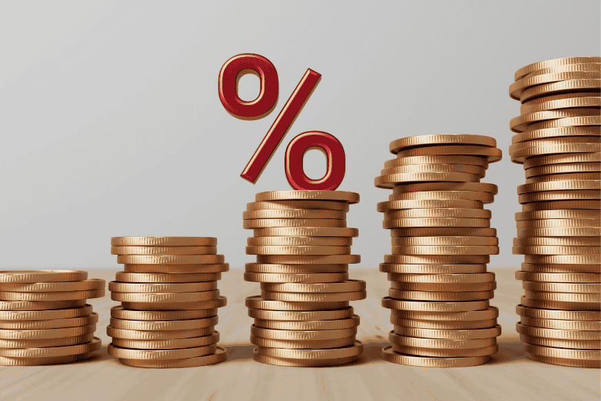 Piles de pièces avec un symbole de pourcentage rouge, représentant le calcul du taux d’endettement en finance personnelle.

