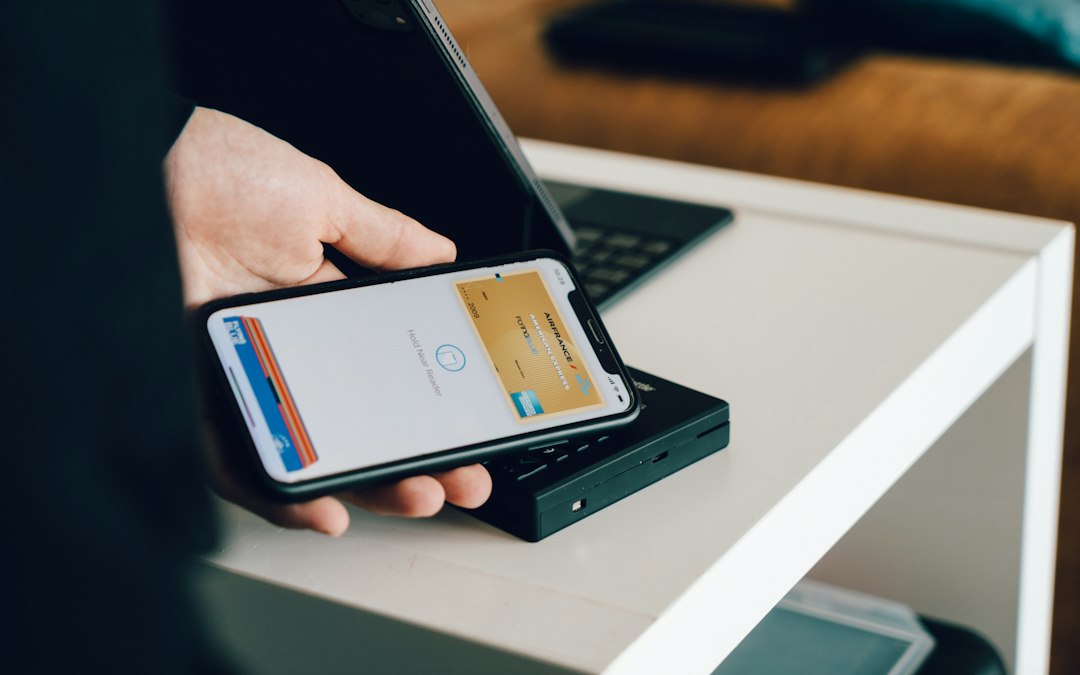 A person holding a smartphone over a card reader for contactless payment
