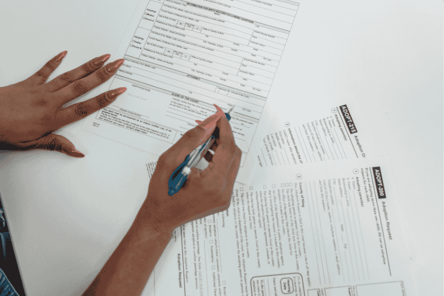 Personne remplissant un formulaire administratif, illustrant les démarches nécessaires pour constituer un dossier de prêt à taux zéro en actuellement.