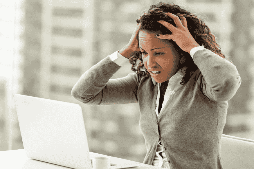 Femme stressée devant son ordinateur en raison de mauvaises décisions financières à éviter pour mieux gérer son argent.