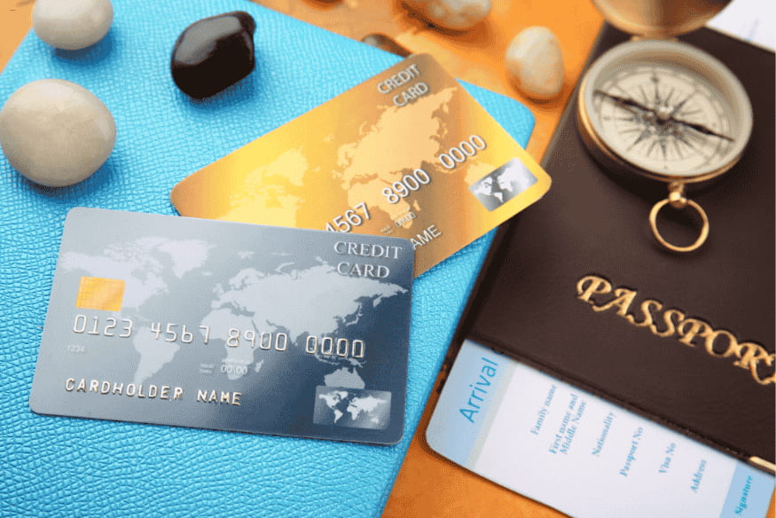 Deux cartes de crédit posées sur un passeport et une boussole, prêtes pour un voyage international.