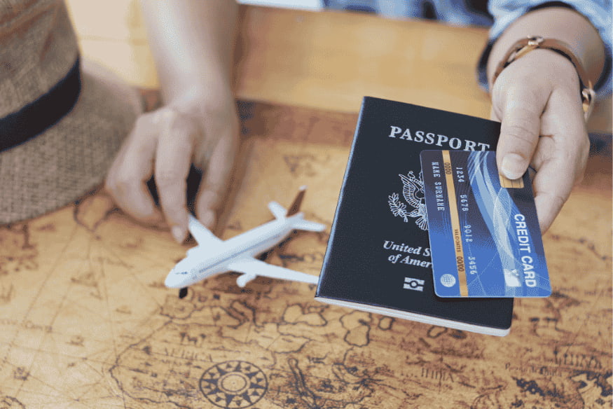 Passeport américain et carte de crédit tenus en main au-dessus d’une carte de navigation.