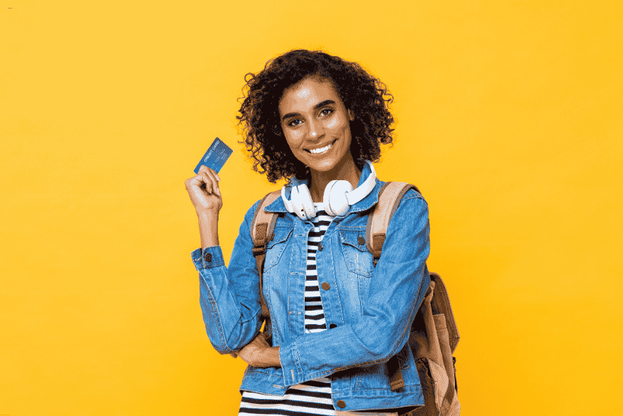 Jeune femme tenant une carte bancaire avec un sac à dos et des écouteurs