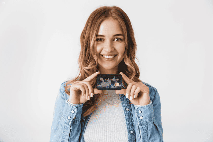 Adolescente souriante tenant une carte bancaire, illustrant l’utilisation des cartes prépayées pour les jeunes.