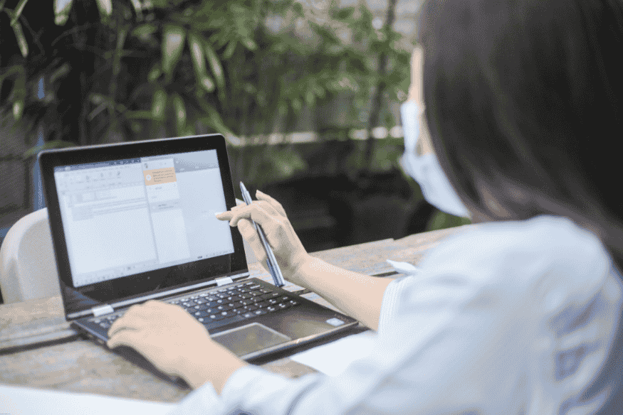Femme consultant des offres de crédit sur un ordinateur portable, dans un environnement extérieur.