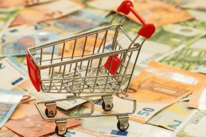 Chariot miniature posé sur une pile de billets en euros de différentes valeurs.
