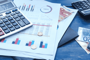 Vue de documents financiers avec graphiques, pièces en euros, billets et calculatrice.