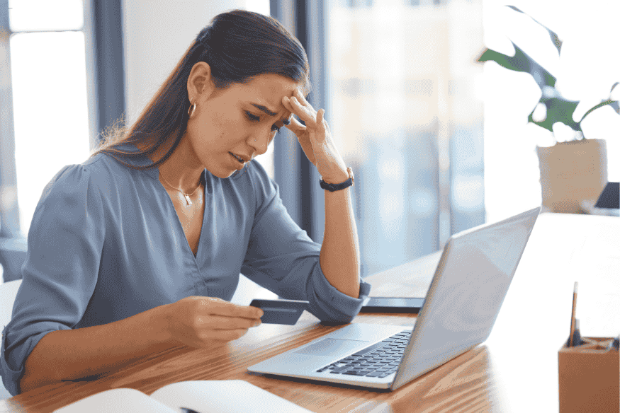 Femme inquiète consultant son ordinateur après un refus de carte bancaire en ligne.
