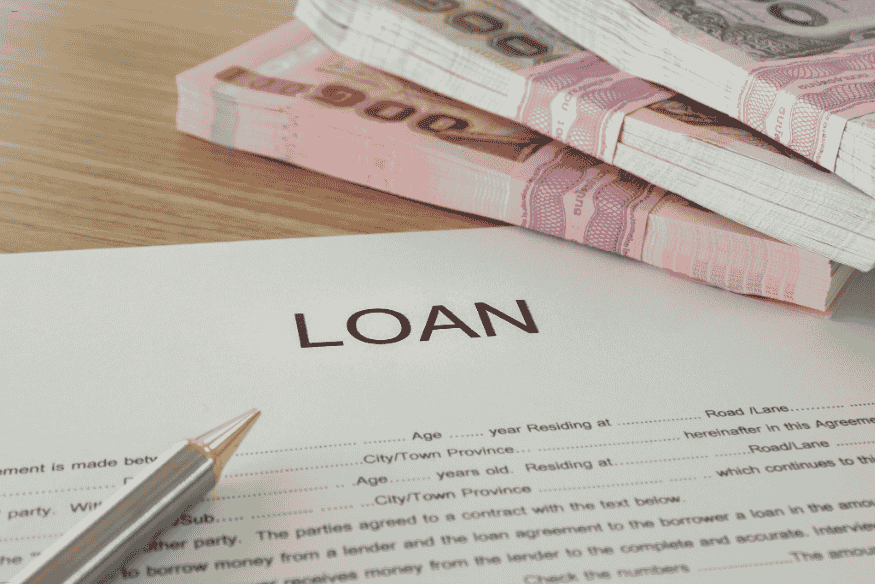 Document marqué “LOAN” accompagné de liasses de billets et d’un stylo, prêt à être signé.