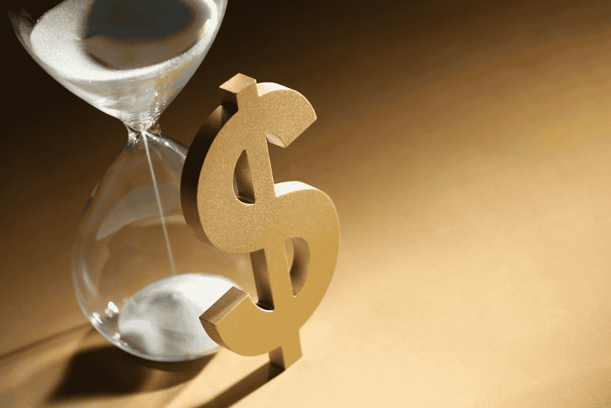 Sablier à côté d’un symbole dollar en or représentant le temps et la gestion financière pour sortir du découvert.
