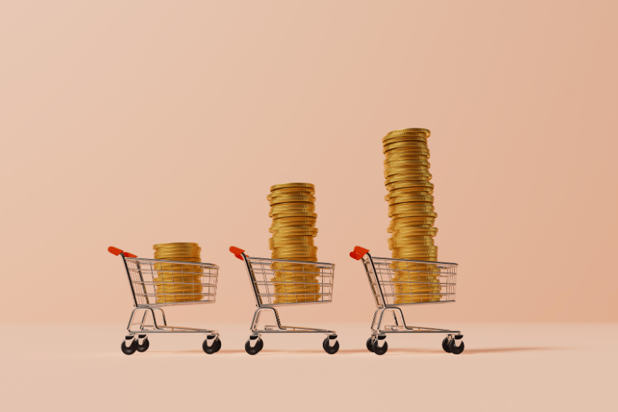 Trois chariots de supermarché contenant des piles croissantes de pièces, illustrant l’évolution des dépenses variables dans le budget personnel.