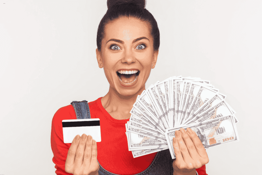 Femme souriante tenant une carte bancaire et une grande liasse de billets.