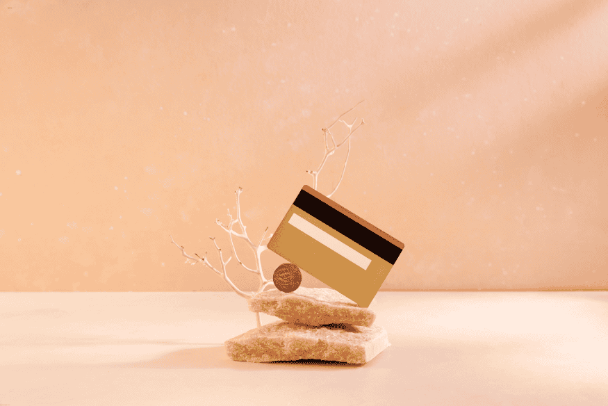 Carte bancaire premium dorée posée sur des pierres dans un décor minimaliste.