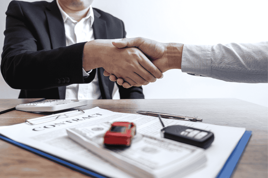 Poignée de main entre deux personnes signant un contrat de financement automobile en France, avec argent, clés de voiture et miniature.