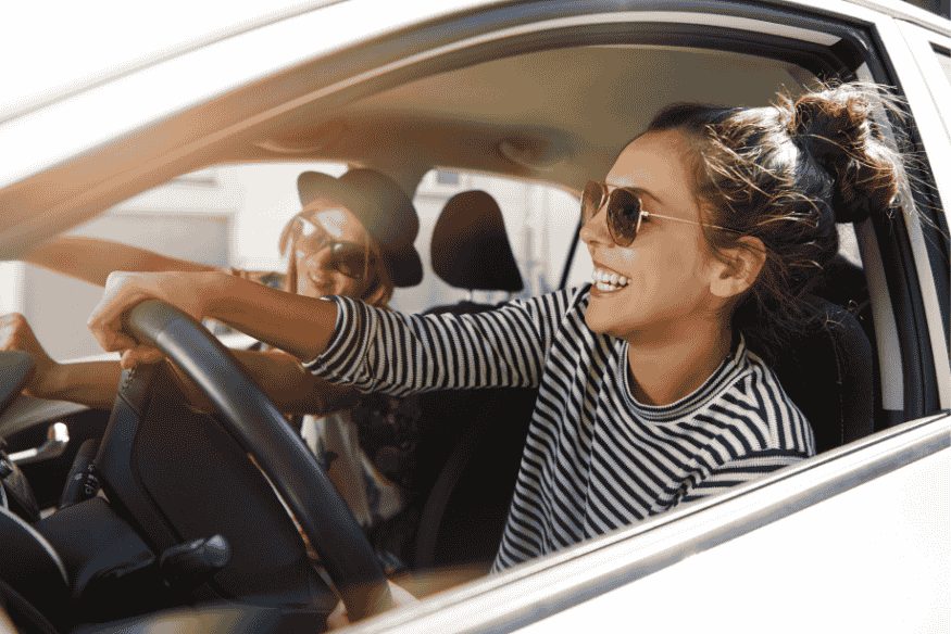 Jeune femme souriante au volant de sa voiture, illustrant la liberté offerte par un bon choix de financement auto.