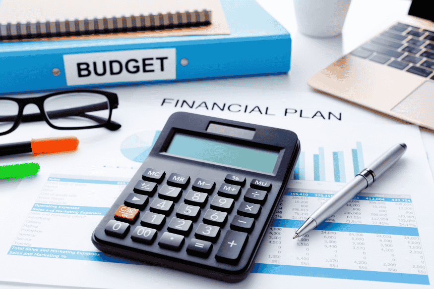 Calculatrice posée sur un plan financier avec un classeur « Budget », illustrant l'intégration des défis d’épargne dans une stratégie financière complète.