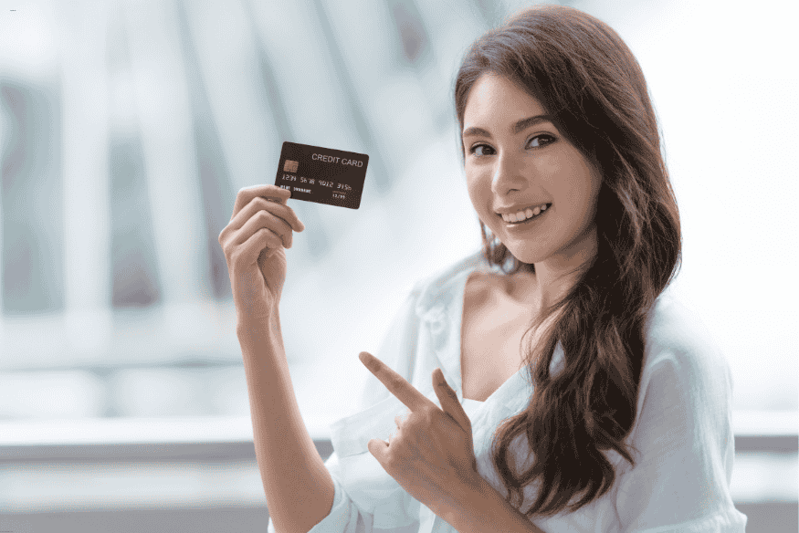 Femme souriante montrant une carte de crédit, illustrant l’obtention facile d’une carte en ligne.