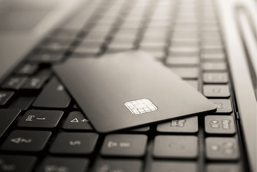 Carte de crédit noire sur un clavier d’ordinateur, illustrant les services bancaires numériques modernes.
