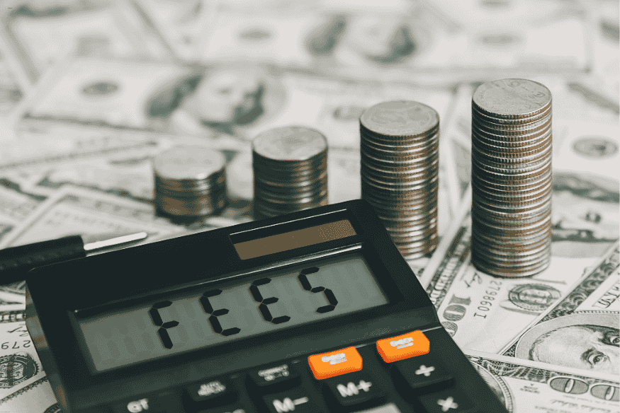Calculatrice sur des dollars affichant “FEES”, entourée de pièces, symbolisant les frais bancaires.