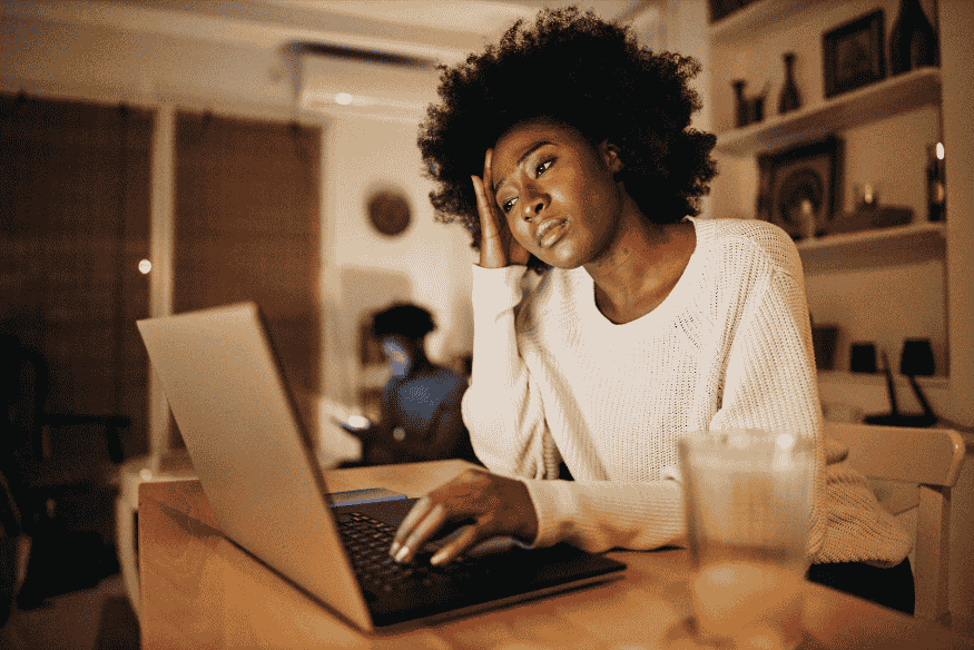 Femme préoccupée devant un ordinateur, illustrant les difficultés de gestion financière avec un revenu irrégulier.