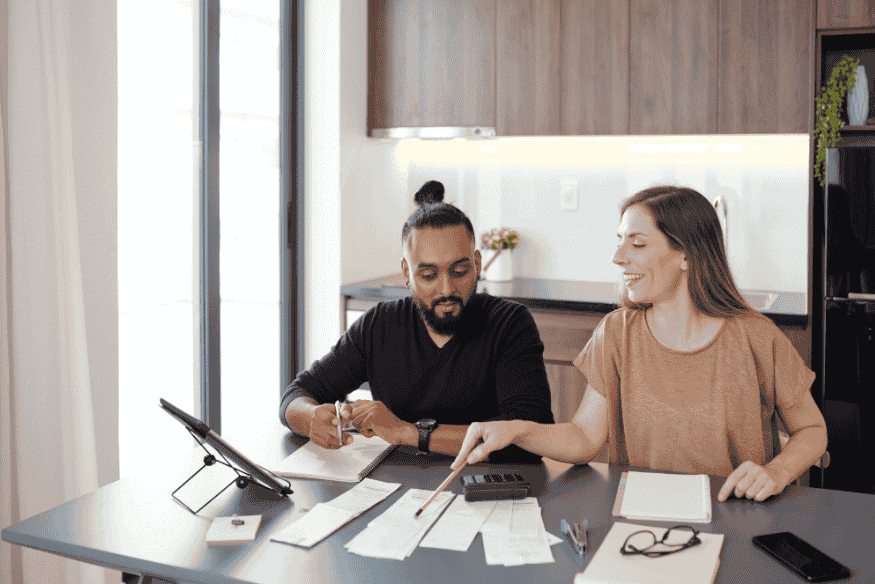 Couple utilisant une calculatrice et des reçus pour organiser un système budgétaire hybride adapté à leurs finances.
