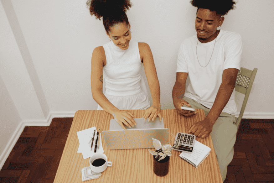 Couple heureux planifiant leur budget mensuel sur un ordinateur pour assurer une stabilité financière à long terme.