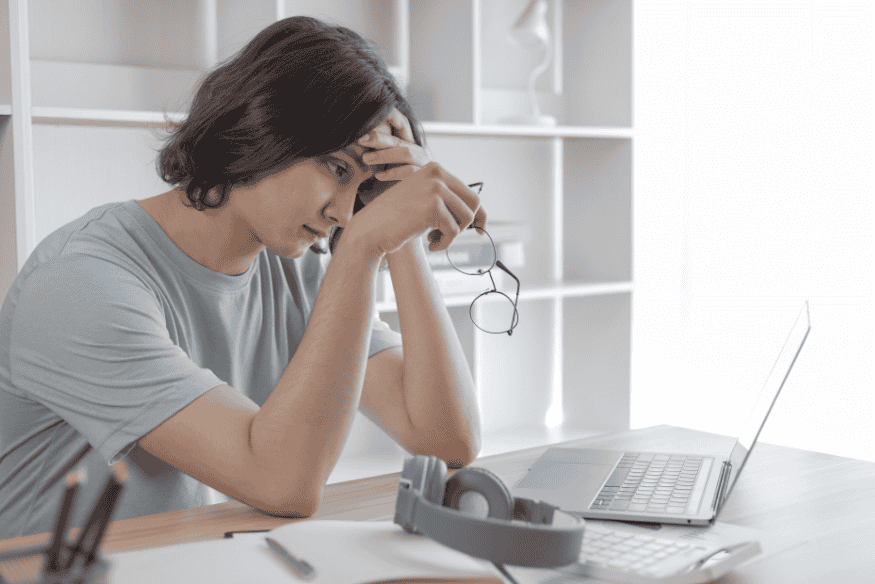Jeune homme stressé devant un ordinateur portable, illustrant les erreurs courantes dans la gestion financière personnelle en 2025.