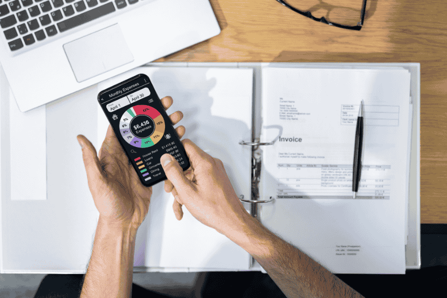 Personne consultant une application mobile de gestion des dépenses mensuelles avec un graphique circulaire détaillé.
