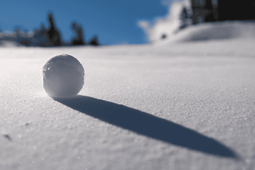Boule de neige en train de rouler sur une pente enneigée, illustrant le concept de la méthode boule de neige pour rembourser ses dettes.
