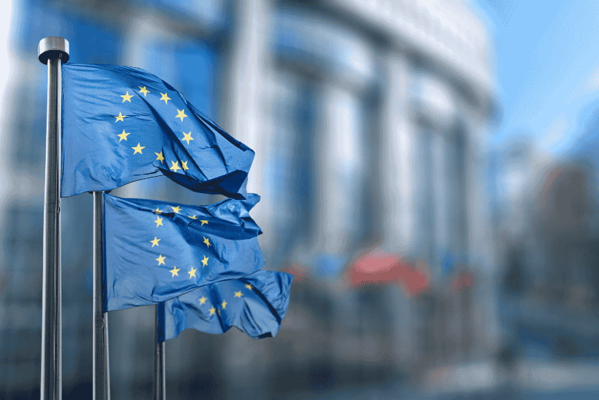 Drapeaux de l’Union européenne devant un bâtiment institutionnel, symbolisant la diversité culturelle et économique en Europe.