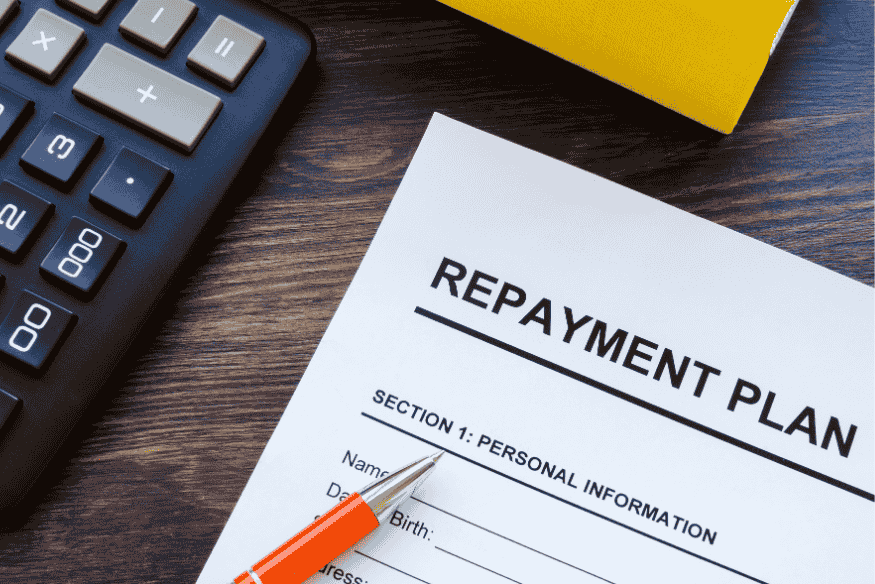 Formulaire de plan de remboursement avec calculatrice et stylo sur une table, représentant les démarches administratives liées au remboursement anticipé d’un prêt.