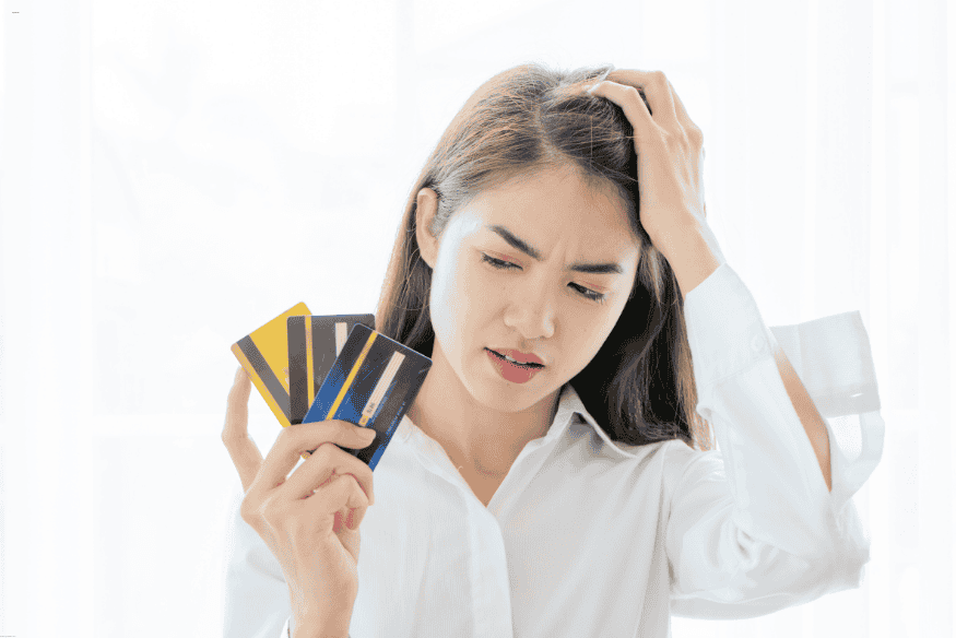 Femme confuse avec plusieurs cartes bancaires, préoccupée par les plafonds de paiement