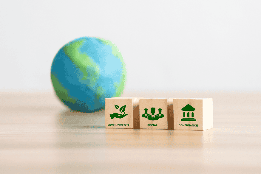 Blocs en bois représentant les piliers ESG (environnemental, social, gouvernance) avec la planète Terre en arrière-plan, illustrant l’impact des moyens de paiement sur la société.
